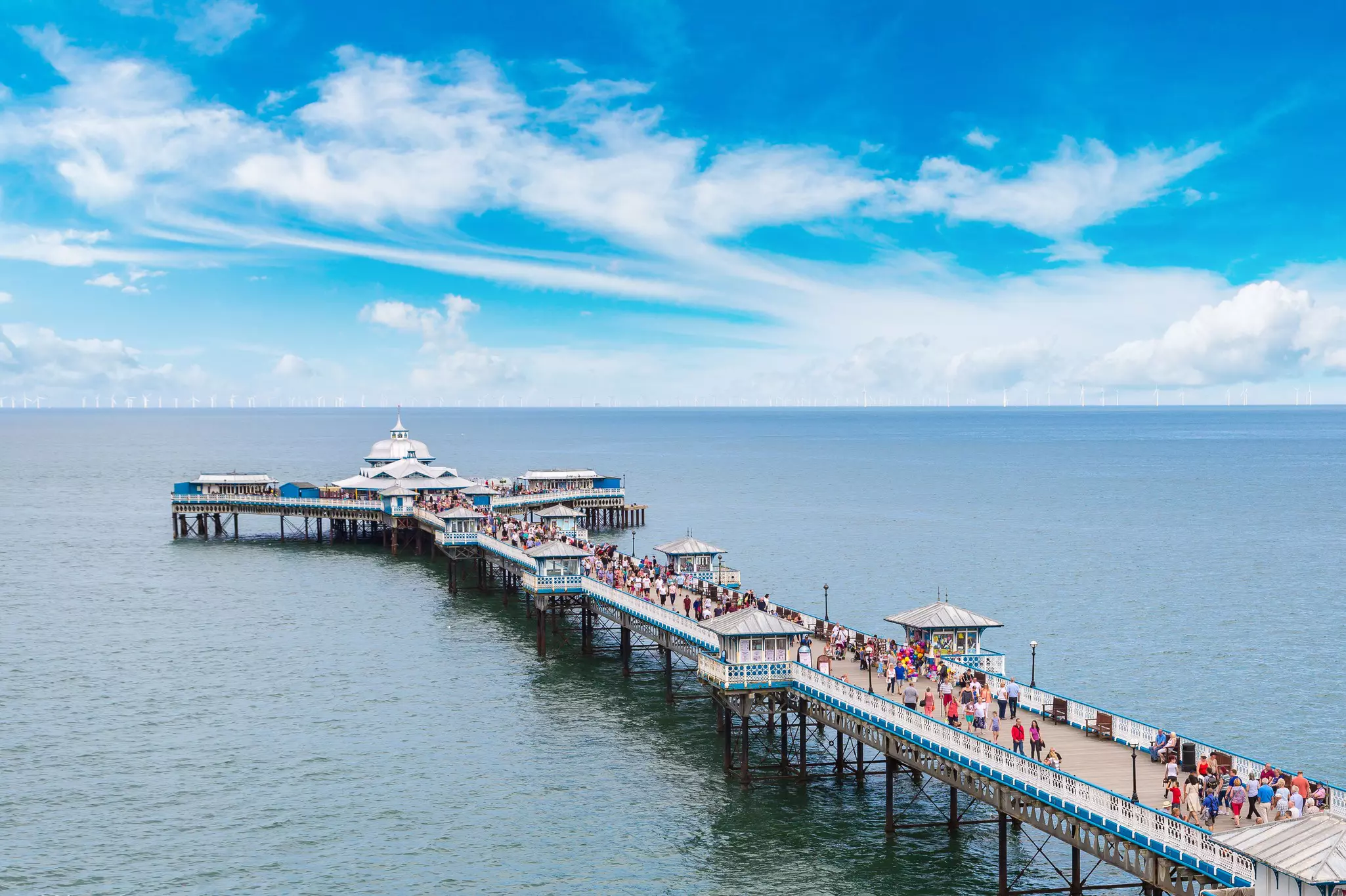 A vast Victorian pier, busy with people, stretches out into the ocean