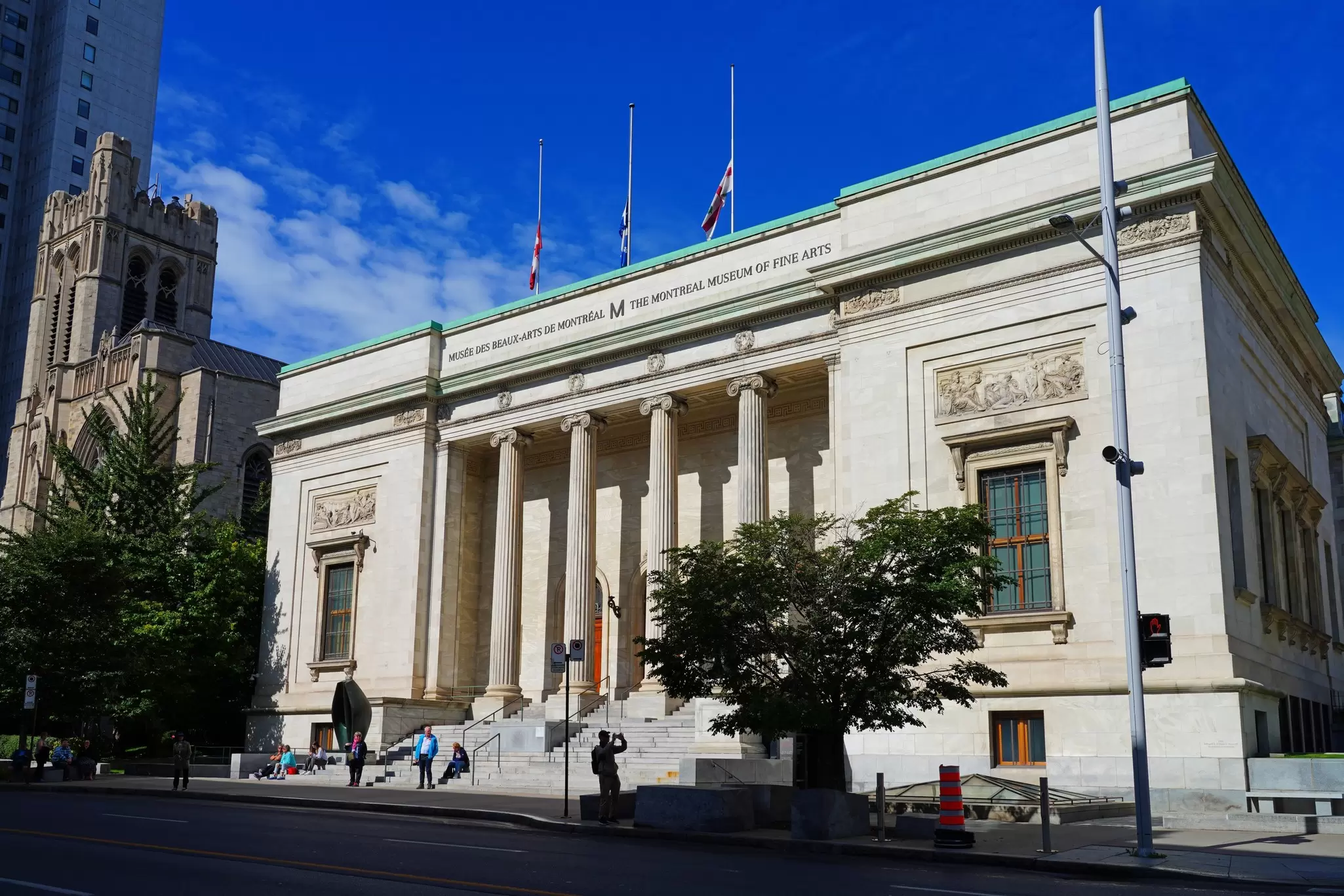 Neoclassical columned facade of the Montreal Museum of Fine Arts under a bright blue sky