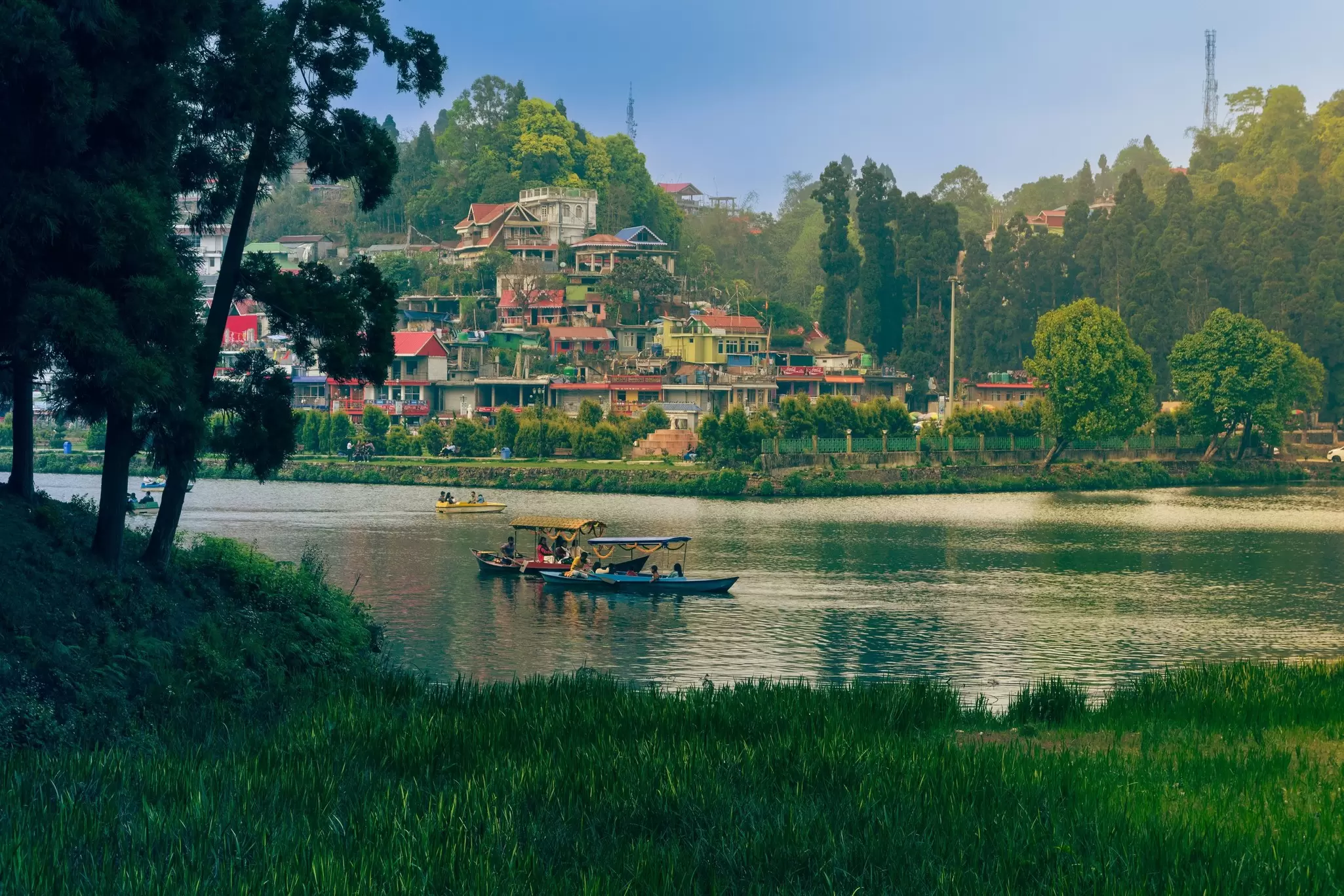 Small wooden boats on a lake in a green mountain hill station.
