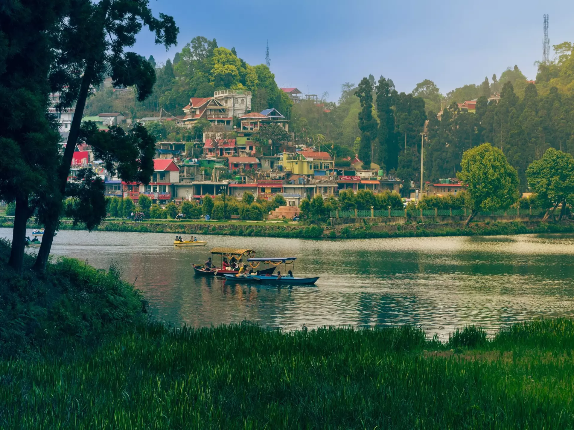 Small wooden boats on a lake in a green mountain hill station.
