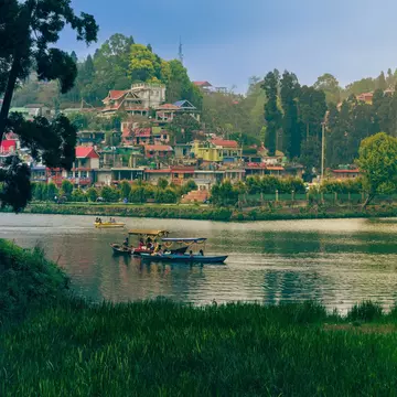 Small wooden boats on a lake in a green mountain hill station.