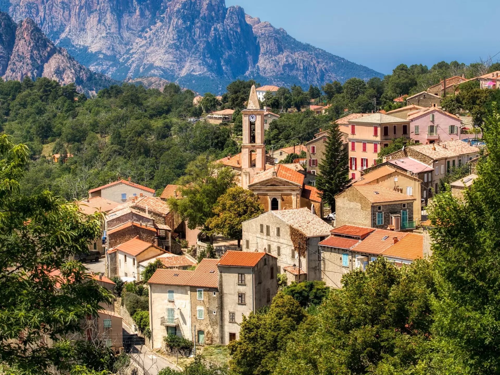 A mountain village peaks out among craggy cliffs and woodland in Corsica