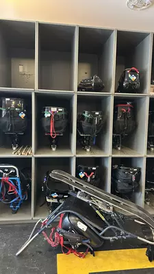 Shelves storing a collection of different sit skis, adapted for skiers with disabilities