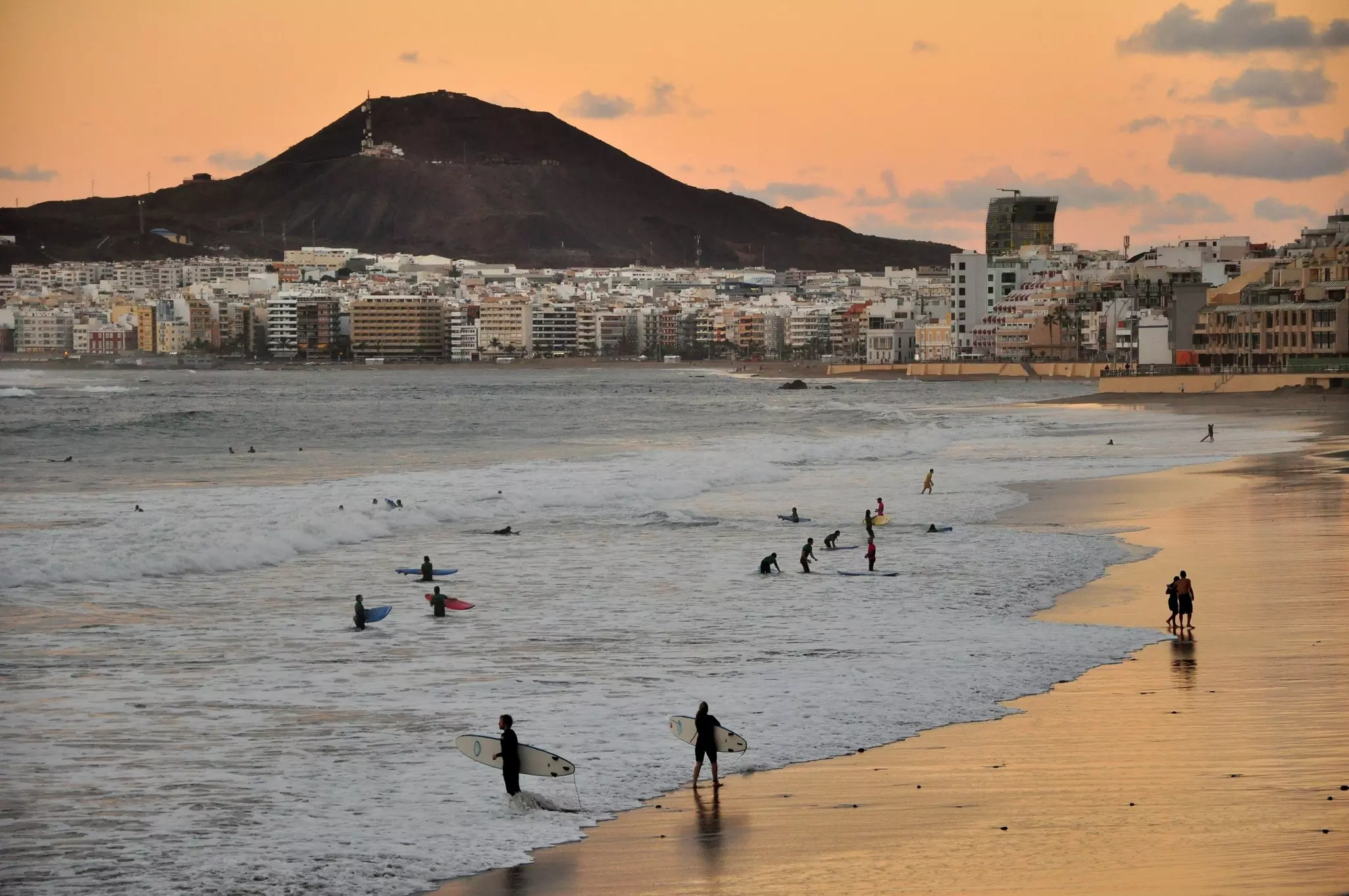 Sunset in Las Palmas de Gran Canaria. Surfers enjoying city beach.