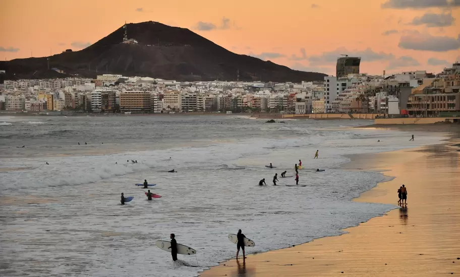 Sunset in Las Palmas de Gran Canaria. Surfers enjoying city beach.