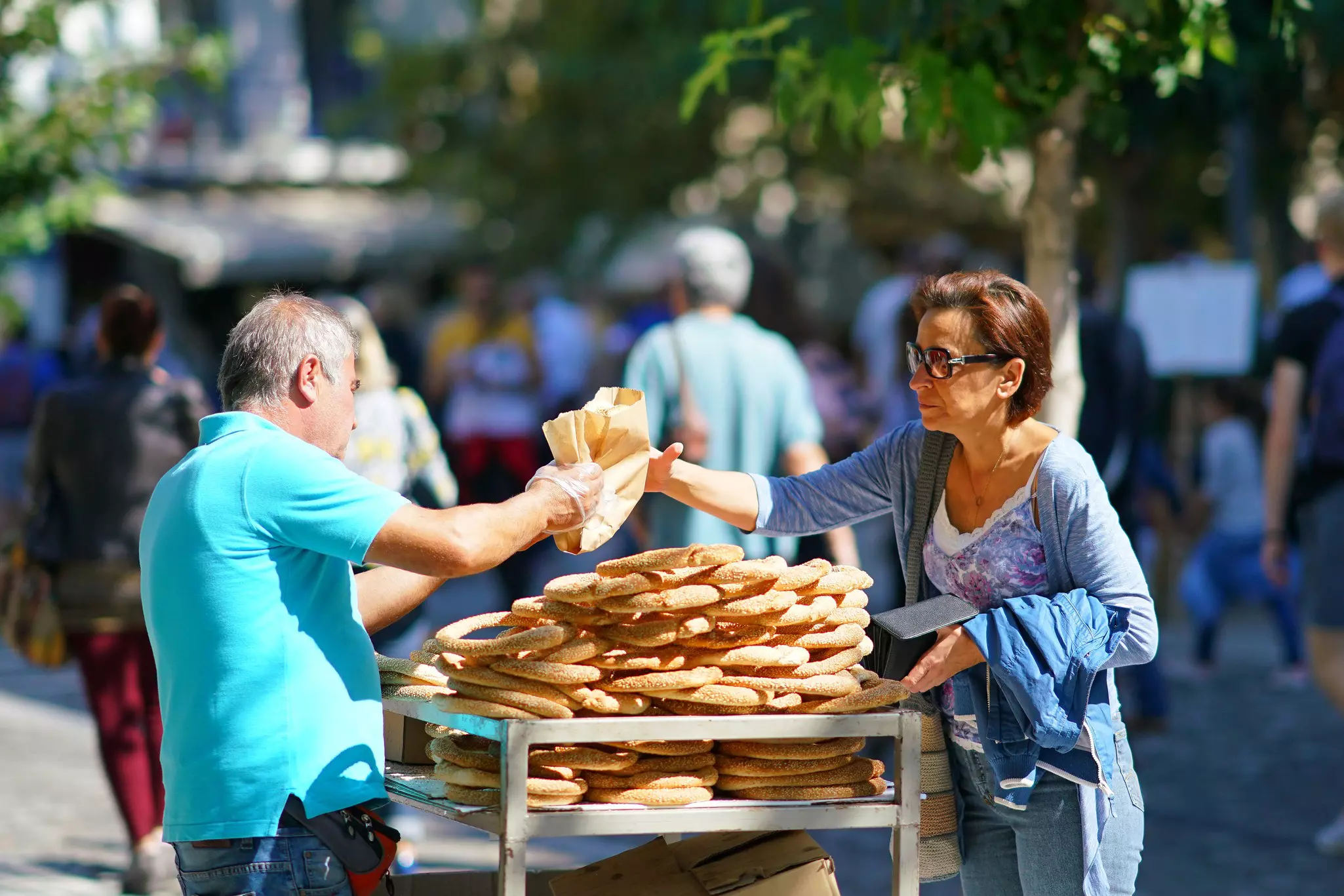 A woman buys bread rings from a street vendor in Athens.