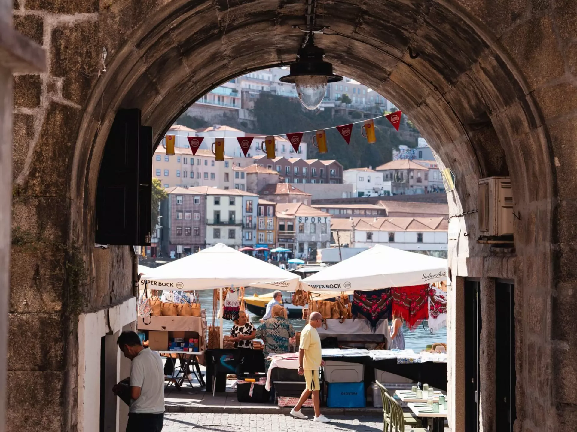 A riverfront market seen through an open stone entrance