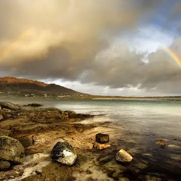 Rainbow stretching over still rural lake