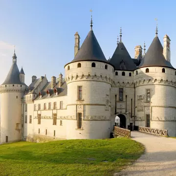 Chaumont Castle in Loire Valley France. Panoramic wide view to the entrance and the garden at sunrise with trees, grass under blue sky.