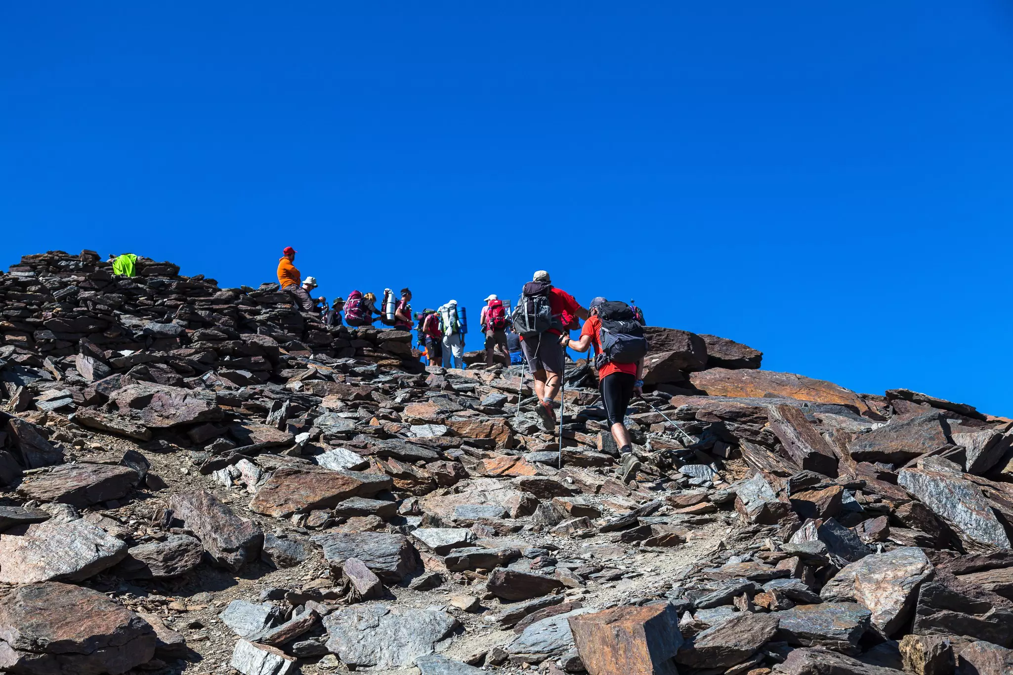 A group of hikers cross a rocky slope to the summit of Mulhacén, Andalucía, Spain.