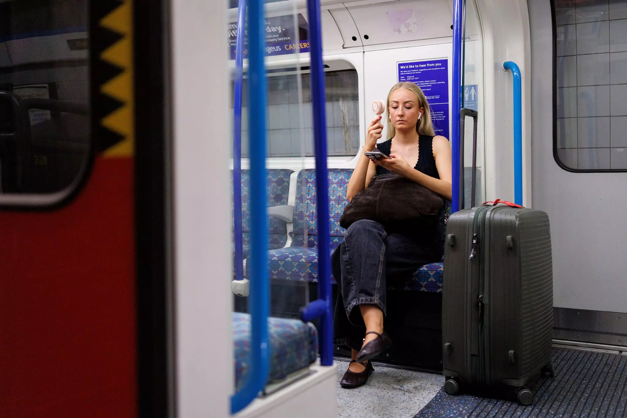 A traveler holds an electric fan to cool down on the London Underground during the heatwave. 