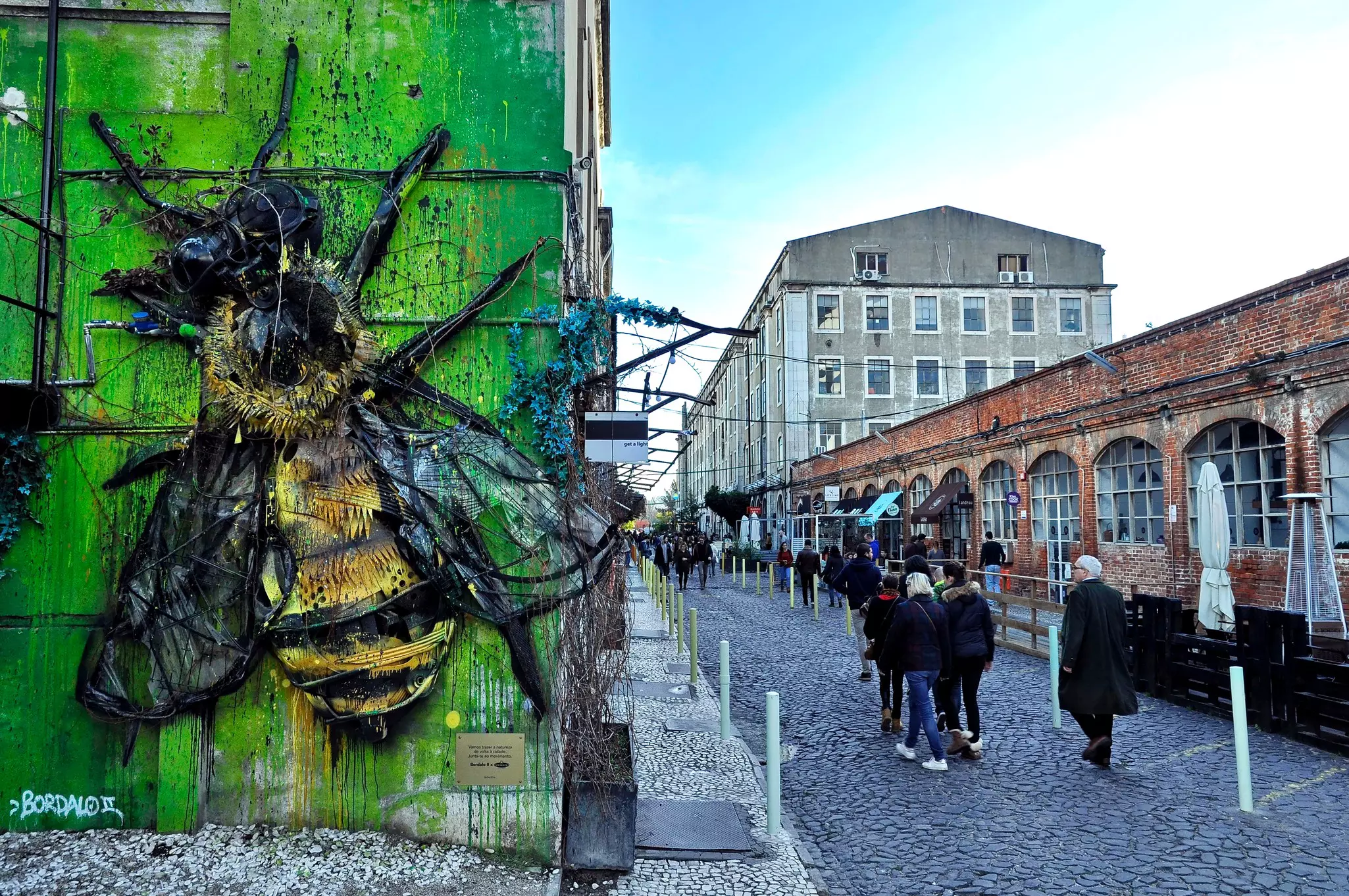 A huge bumble bee sculpture installed on a wall outside a former factory, now shopping center