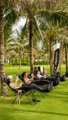 People recline in lounge chairs under palm trees.