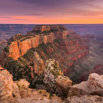 Group of people sitting near the edge watching sunset at Grand Canyon National Park North Rim, USA.