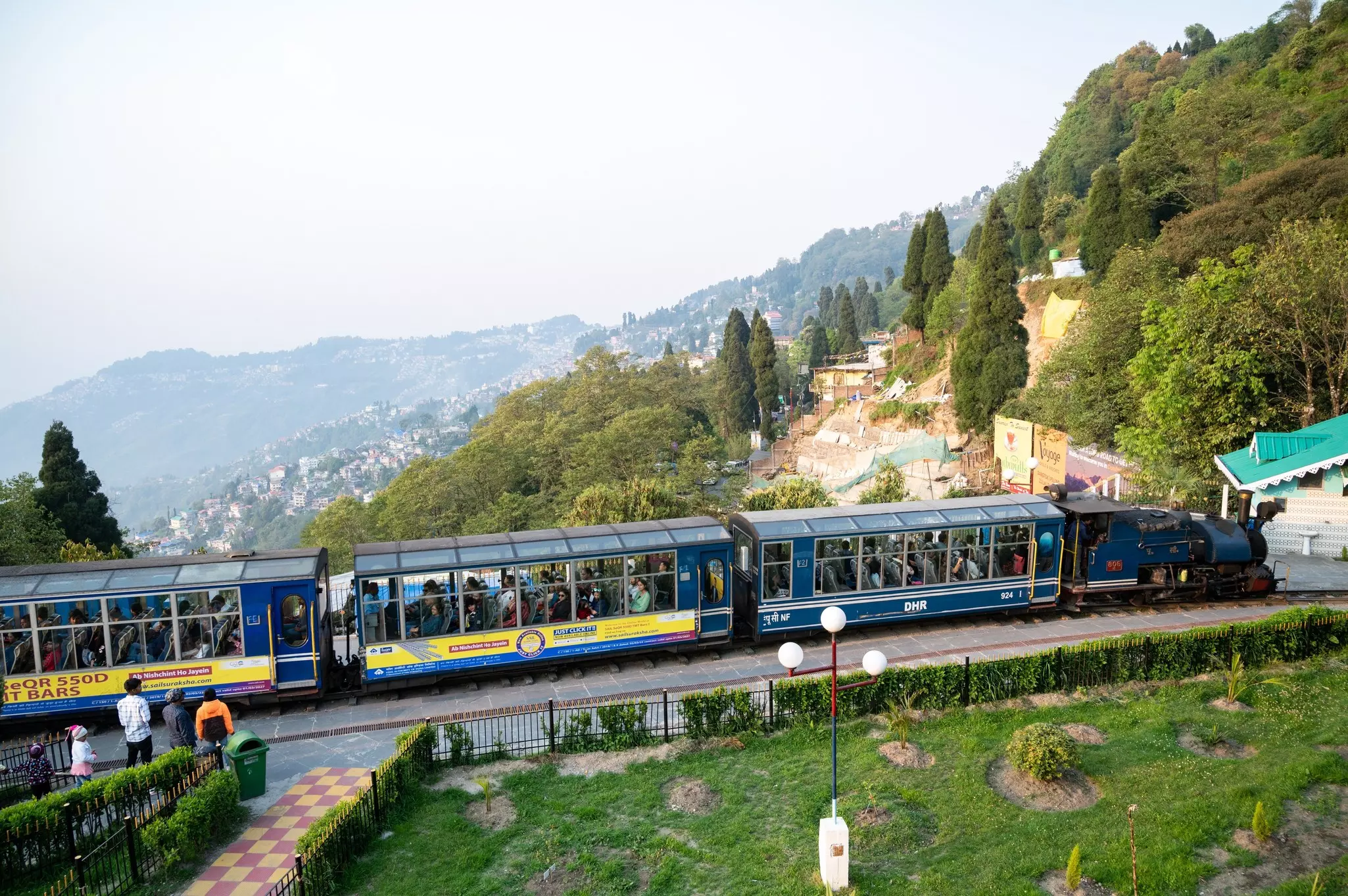 Passengers sit in a small-size tourist train with large windows so they can see the mountain scenery in Darjeeling, India 