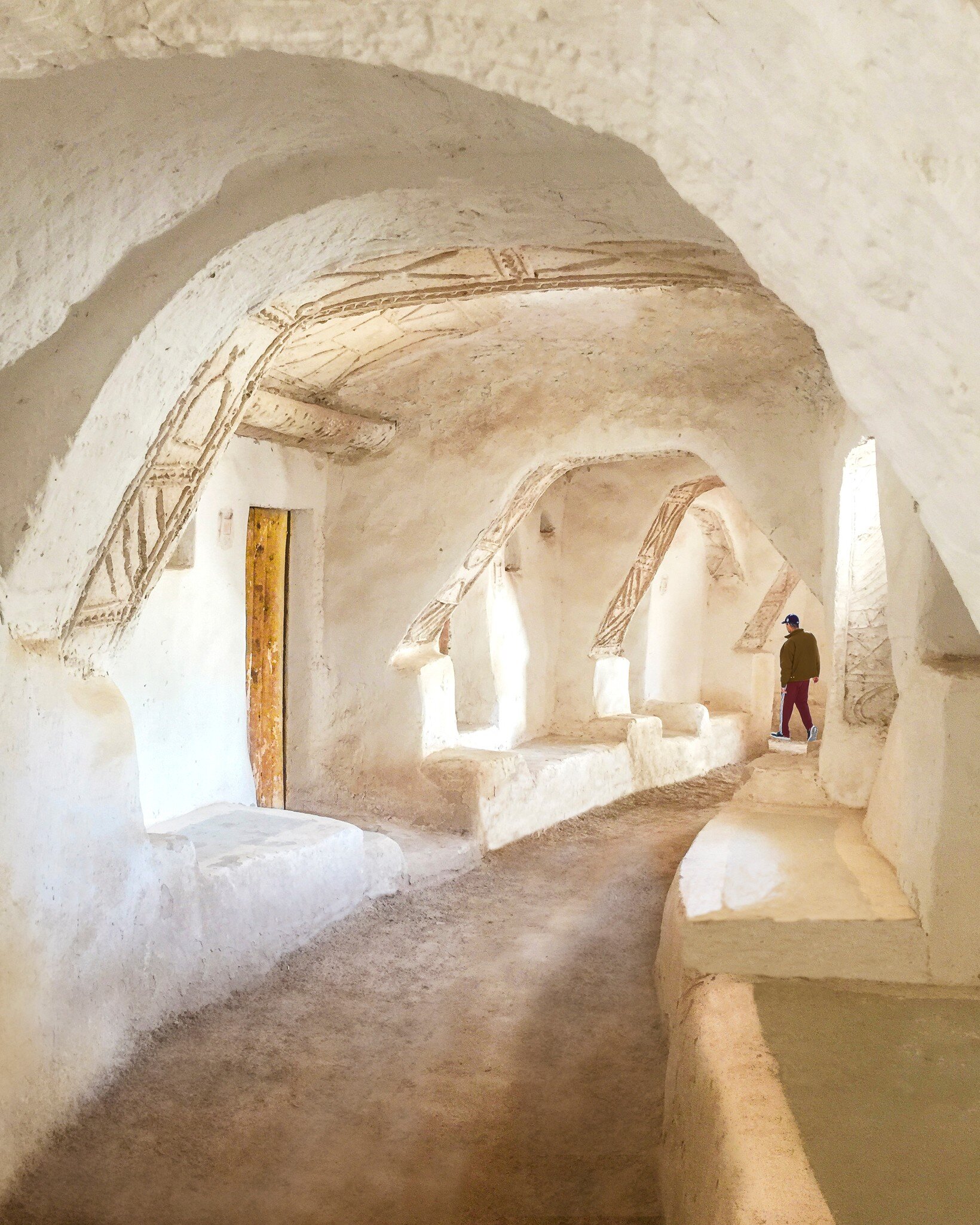 Man walks through whitewashed vaulted passages with carved decoration in the old town of Ghadames, Libya