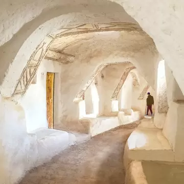 Man walks through whitewashed vaulted passages with carved decoration in the old town of Ghadames, Libya