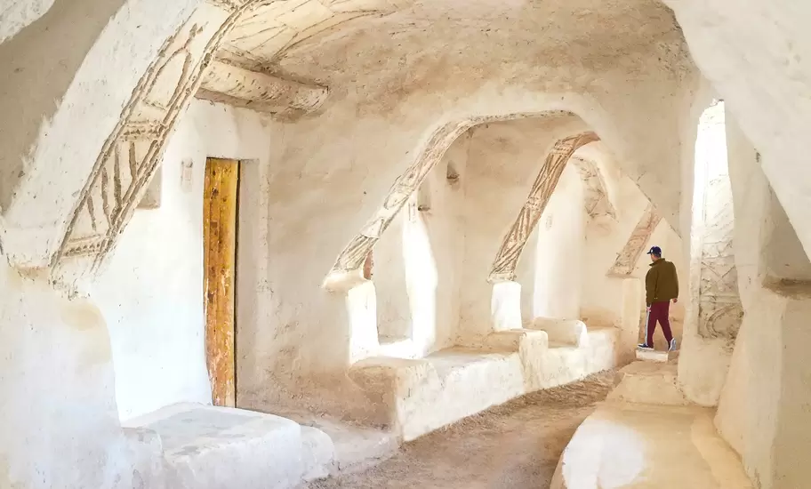 Man walks through whitewashed vaulted passages with carved decoration in the old town of Ghadames, Libya