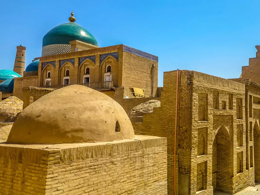Mud brick structures with blue domes and visitors walking the streets