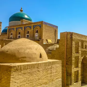 Mud brick structures with blue domes and visitors walking the streets