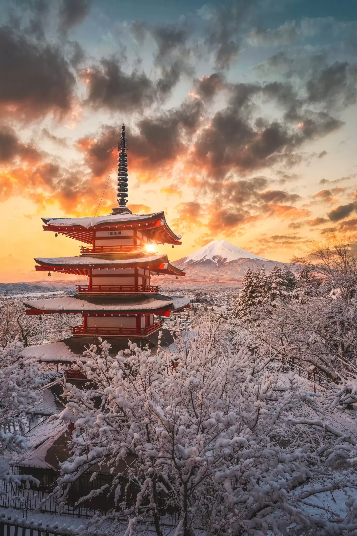 A five-tier red pagoda in a snowy landscape; the sun is partially obscured by one tier.