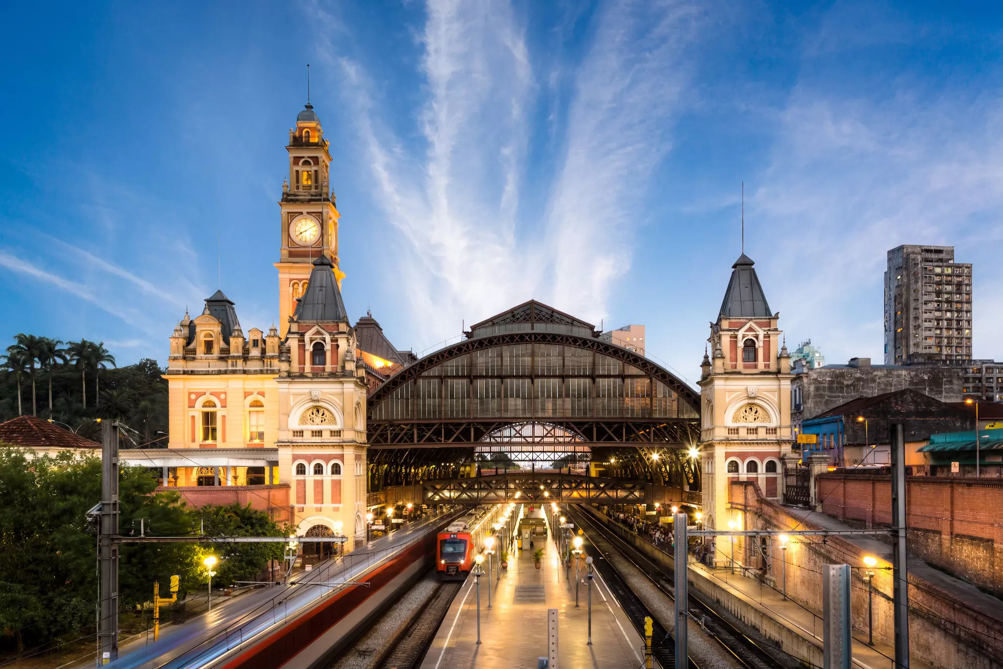A large train and metro station with a clock tower and grand glass and steel awning.
