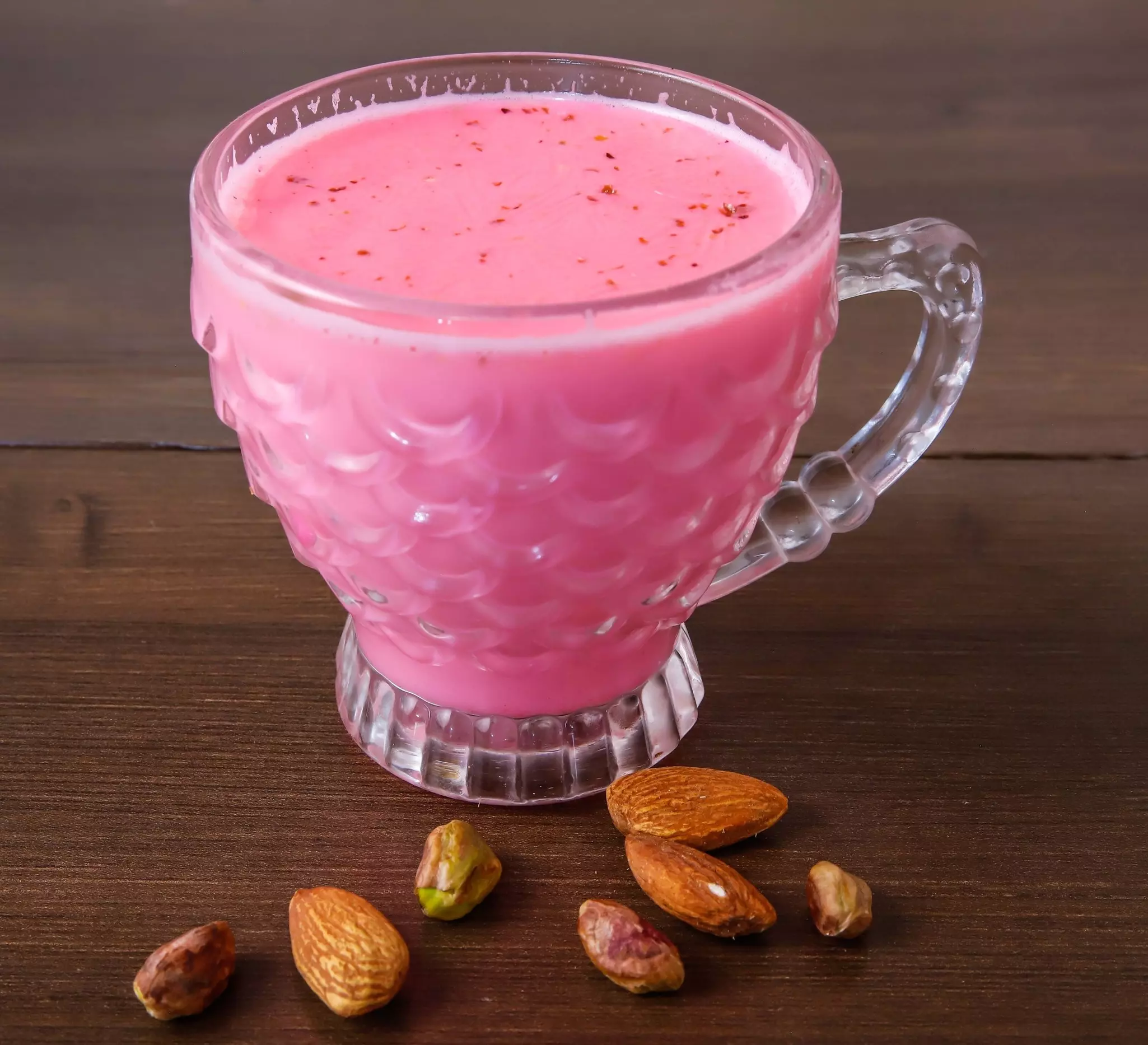 A cup of tea with a pink hue served in a glass.