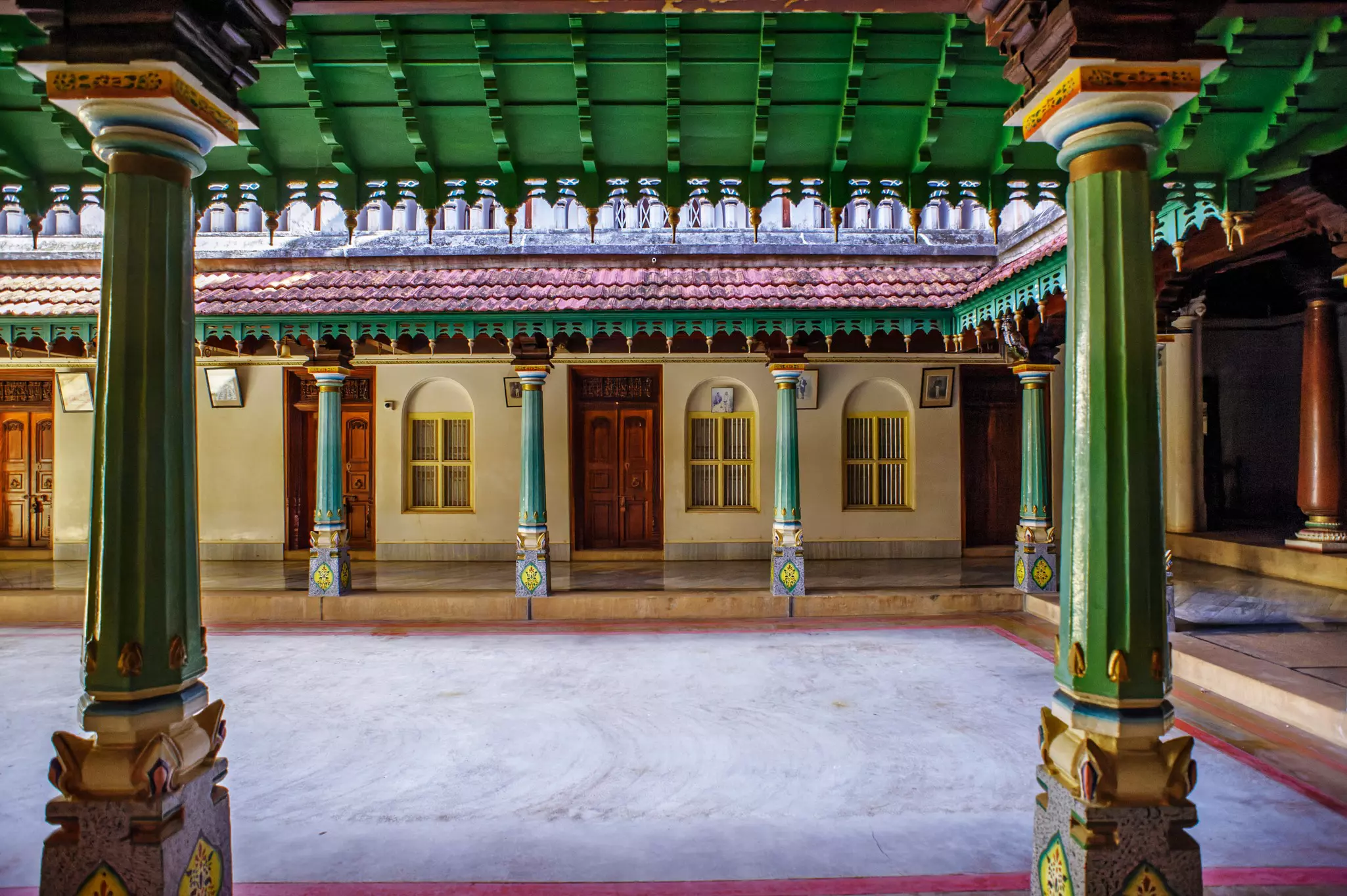 Interior courtyard of a house with a canopy covering a walkway supported by wooden posts