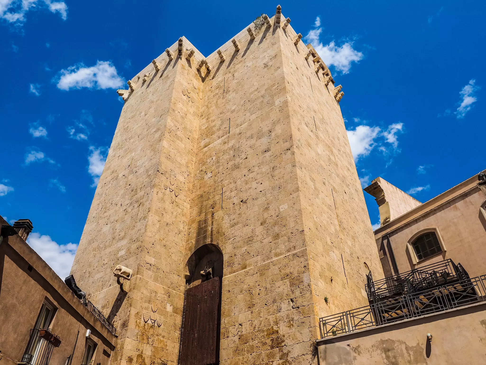 An imposing medieval stone tower with no windows stands below a blue sky.