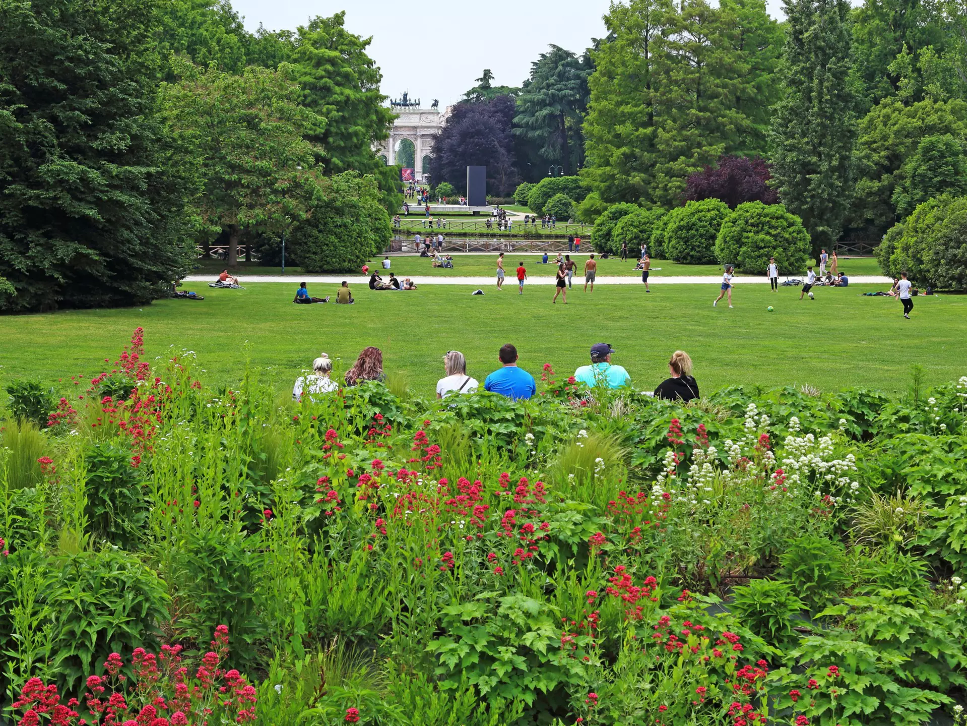 Visitors resting and playing in Sempione Park during the late afternoon.