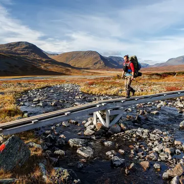 A hiker walks on the Kungsleden Hiking Trail in Swedish Lapland on a sunny day.
