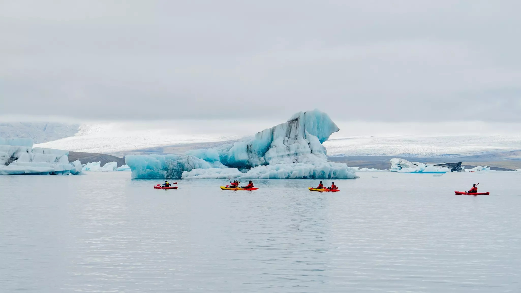 People kayaking around large glaciers.