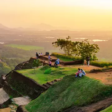 People sitting on Sigiriya Rock in Sri Lanka at sunset.