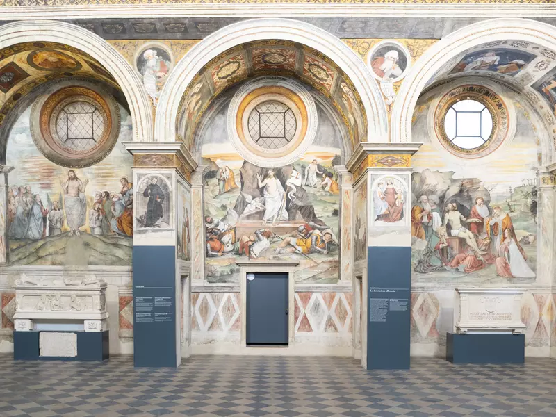 Ornately designed walls with arches, covered in Renaissance paintings in Brescia. 