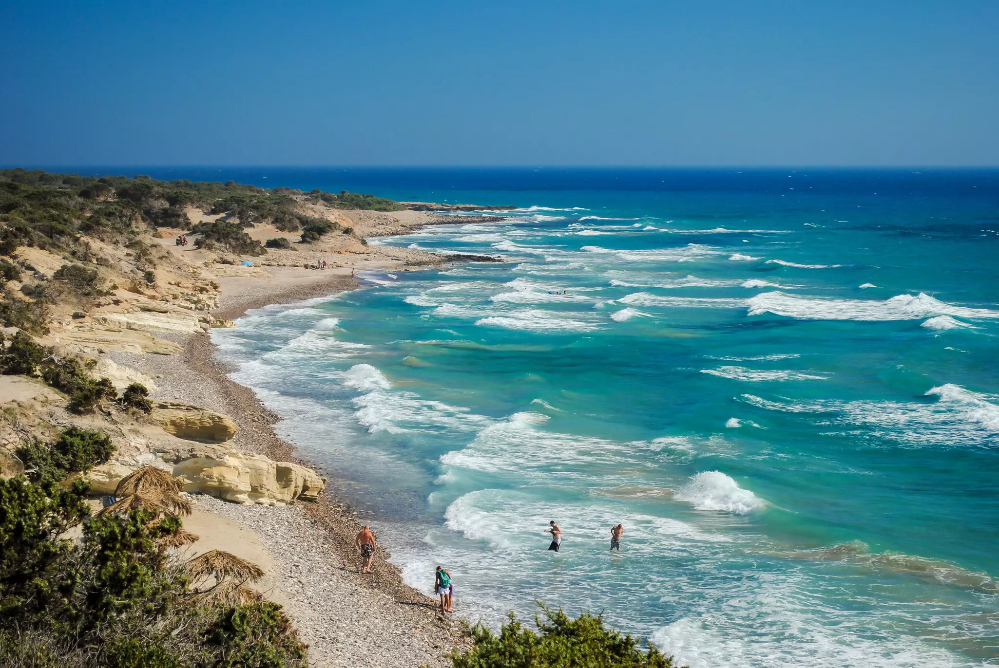 People tread water on a quiet beach in Greece