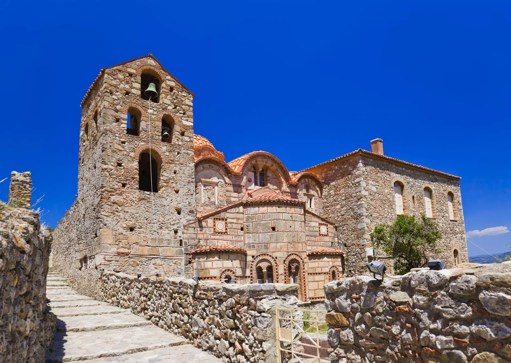 An old stone building in the ruins of Mystras, Greece. The building is a large one, with windows and doors clearly visible.