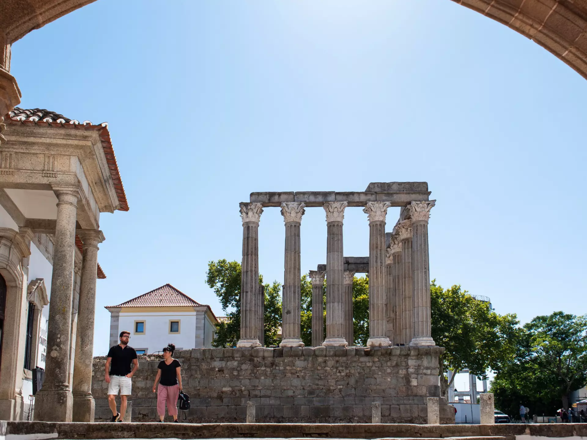 Two people walk by the ruins of a Roman temple in a town