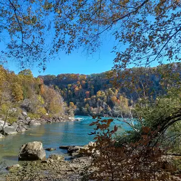 A bend in a turquoise-colored river in Ontario, Canada, is seen from a rocky shore in autumn.