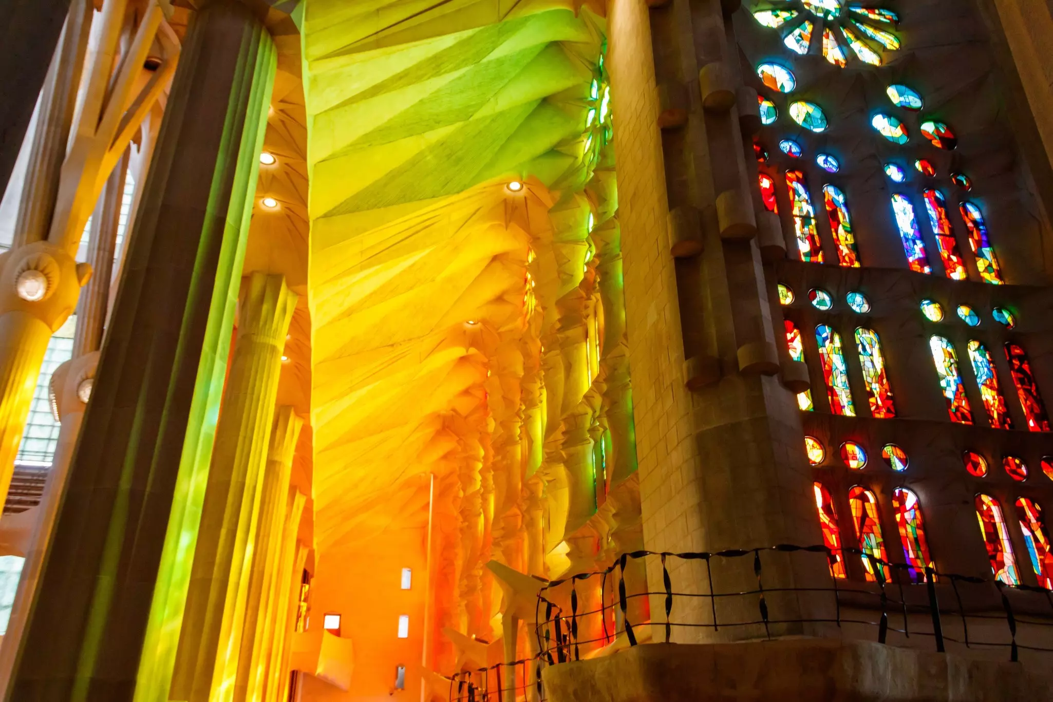 Interior of the La Sagrada Família glowing in neon colors as the sun shines through the stained glass windows