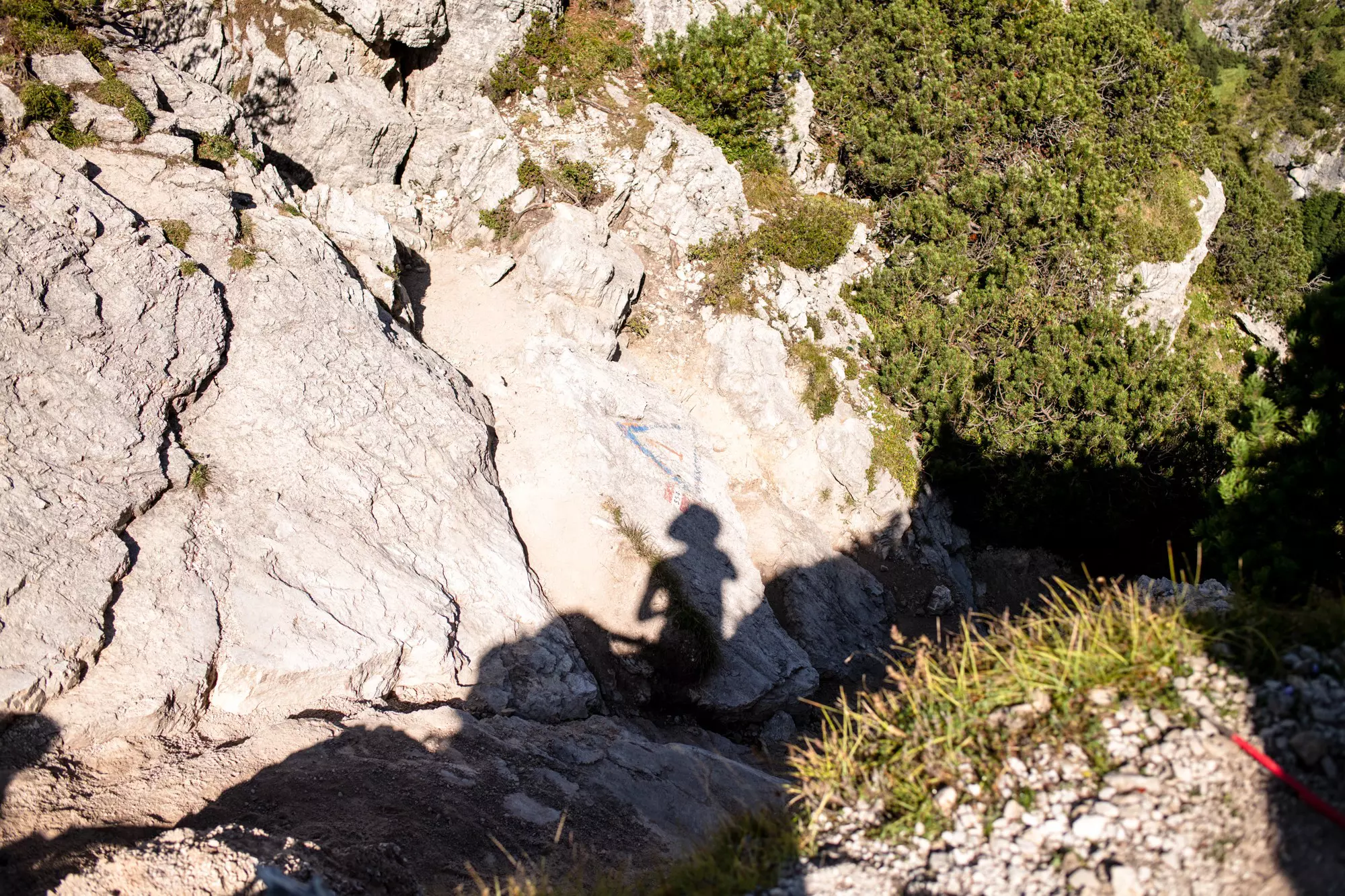The shadow of a hiker taking a photograph on the rocks below on the Alta Via trail in Italy.