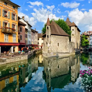 ANNECY, FRANCE - JUNE 22: People drink coffee near the River Thiou in Old Town, encircling the medieval palace perched mid-river - the Palais de l'Isle on June 22, 2014 in Annecy, France.