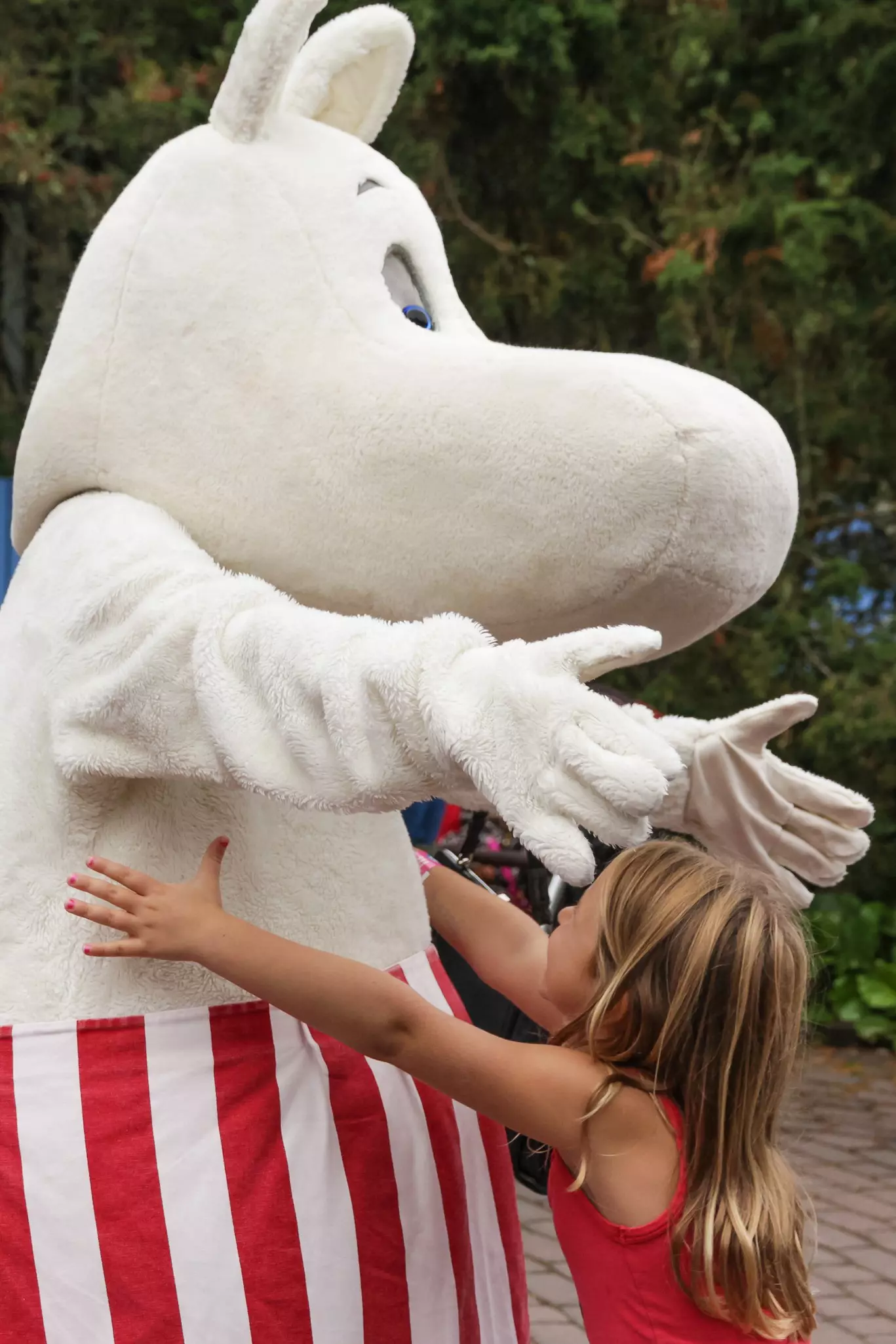 A girl hugs a performer wearing the plush costume of an animated character.