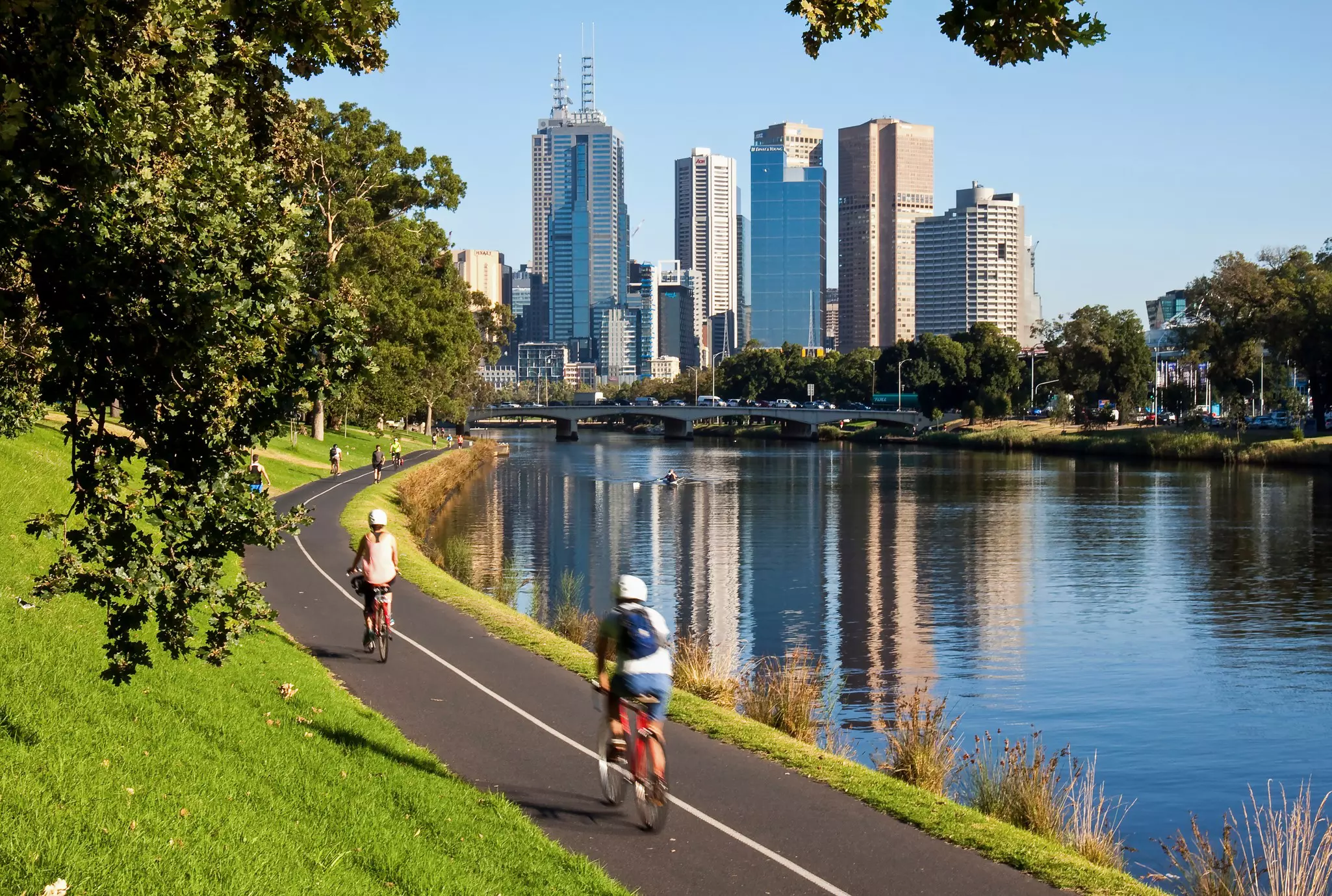 Cyclists riding along the Yarra River toward the center of Melbourne in Australia.