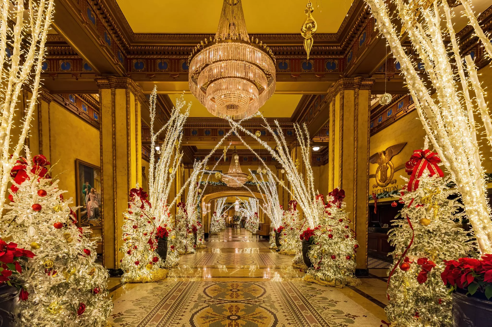 A long, wide hotel corridor with a tiled floor. Christmas decorations and lights fill the hallway.
