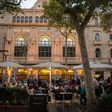 People dining at night outside the Liceu theater facade in Barcelona