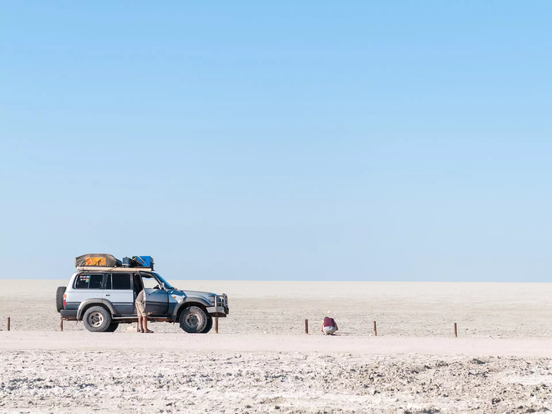 A four-wheel drive vehicle parked up on a gravel road in a flat grey landscape