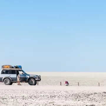 A four-wheel drive vehicle parked up on a gravel road in a flat grey landscape