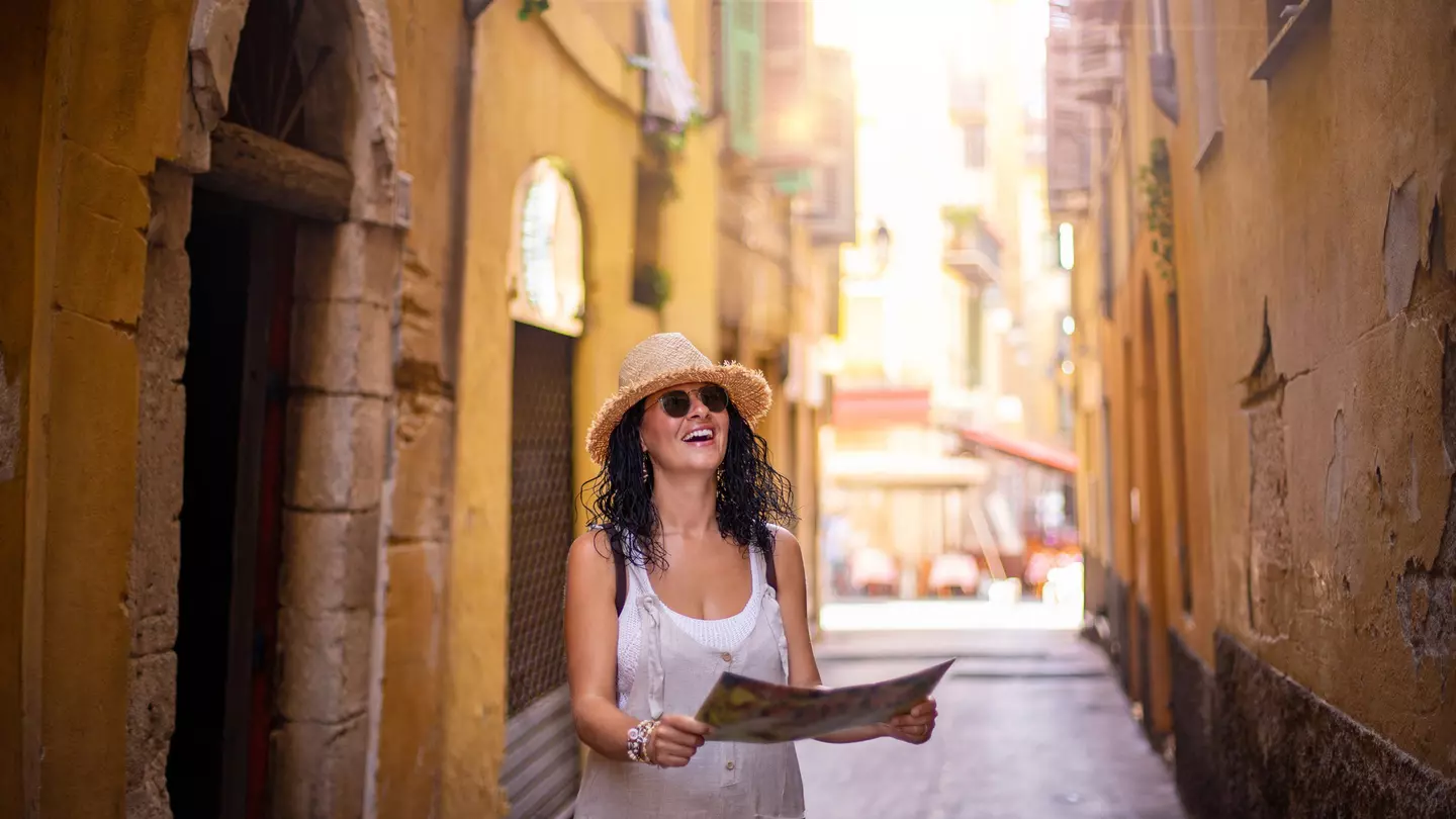 A woman walking along a narrow street in the old town of Nice in France.