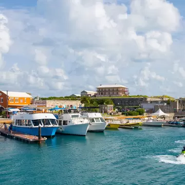 Boats moored at a marina as a person passes by on a jet ski