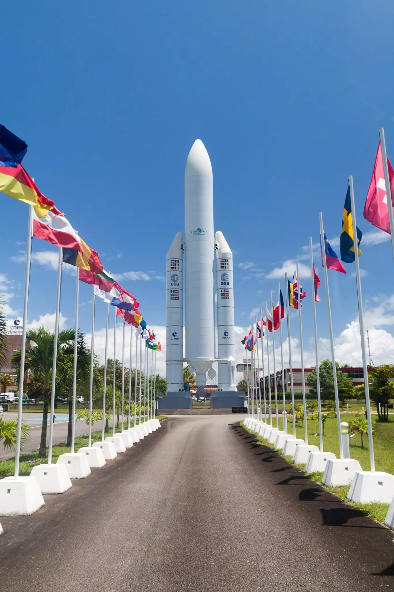 An avenue lined with flags with a huge space rocket standing tall at the end.